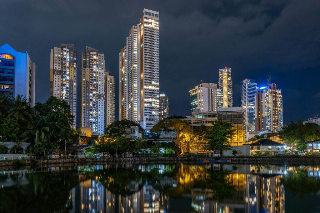 A stunning view of Colombo's skyline at night reflecting on Beira Lake, highlighting urban architecture.